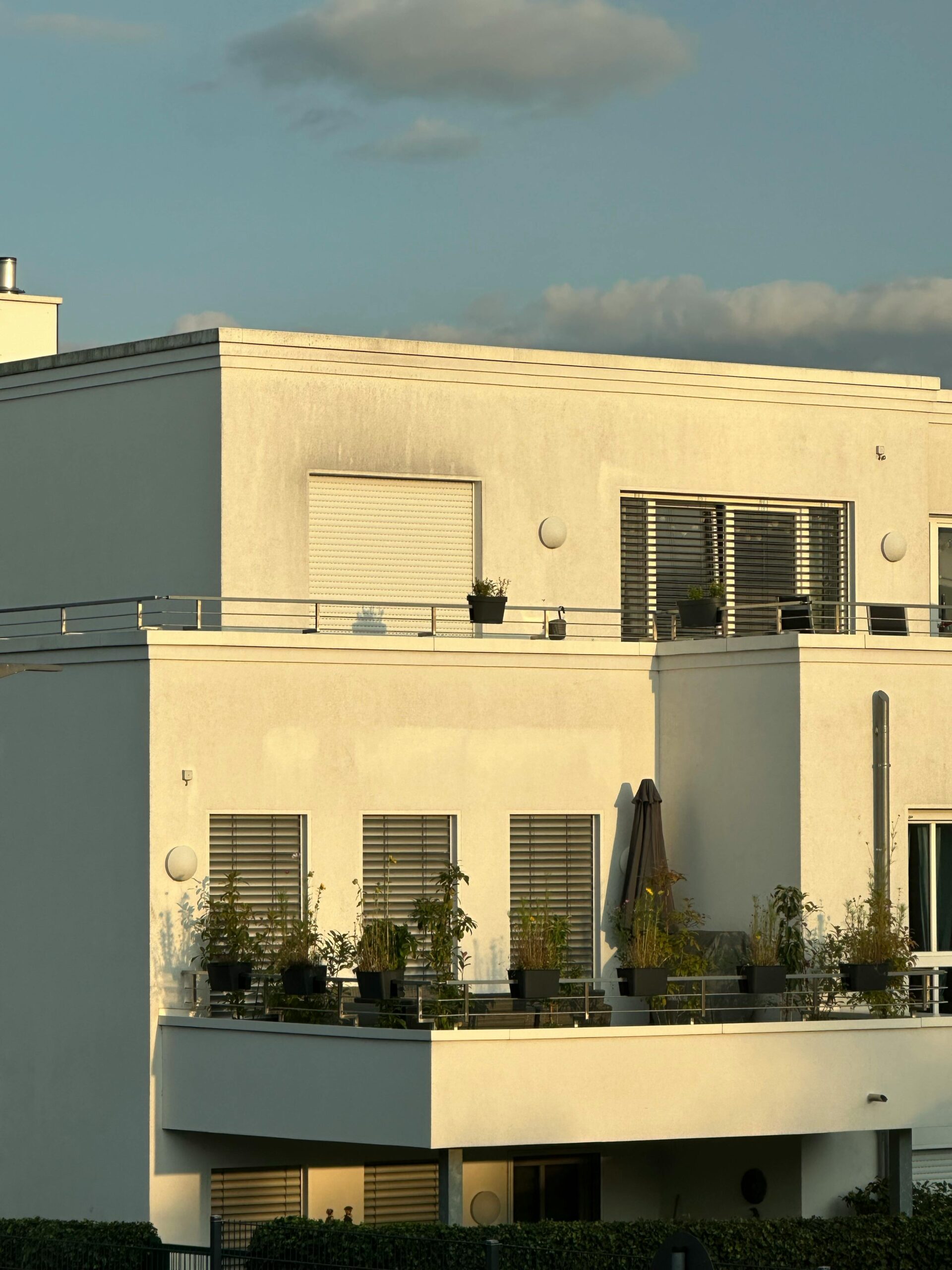Contemporary white apartment building with balconies during golden hour lighting.