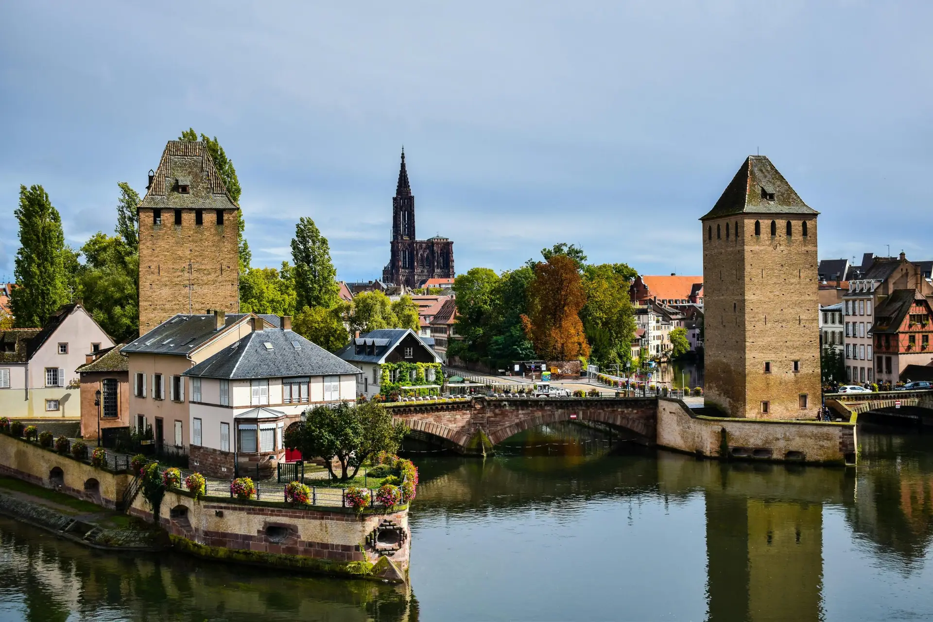 A scenic view of Strasbourg featuring Ponts Couverts and the cathedral in the background.