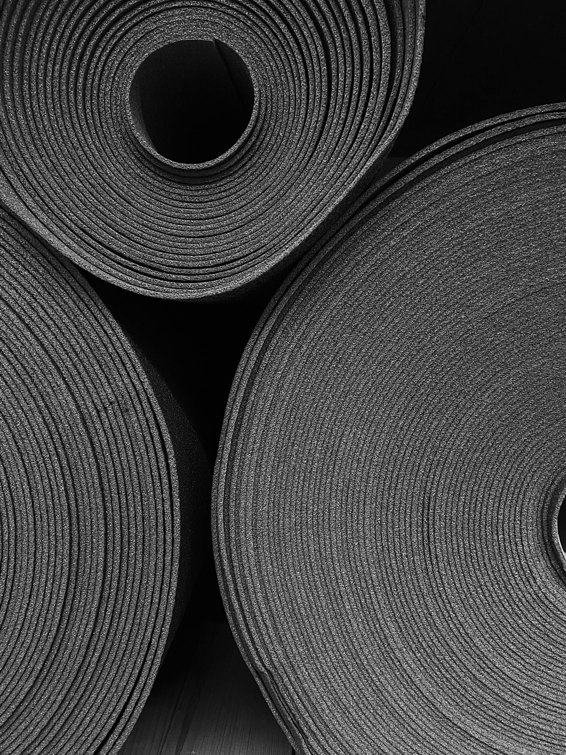 Monochrome photo of stacked rolled yoga mats, perfect for fitness-focused concepts.