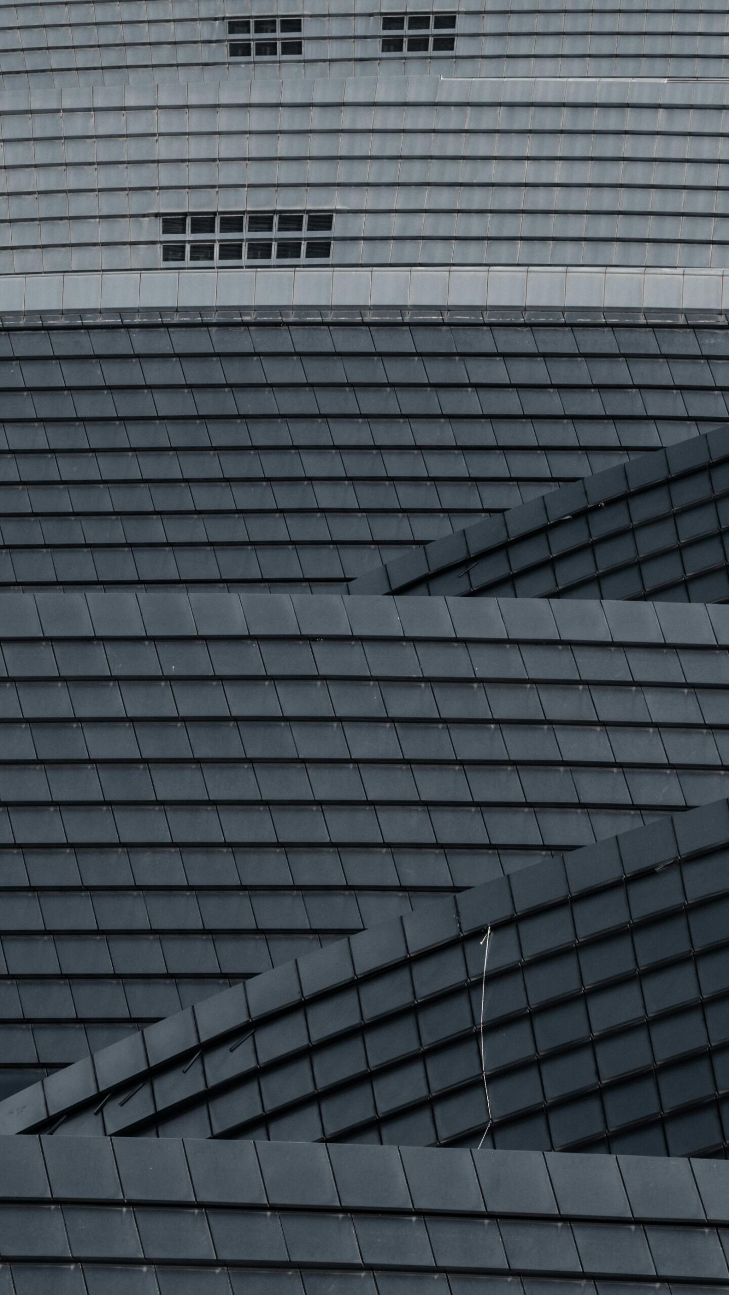 Curved metallic structure with geometric panels and windows in a modern architecture style.