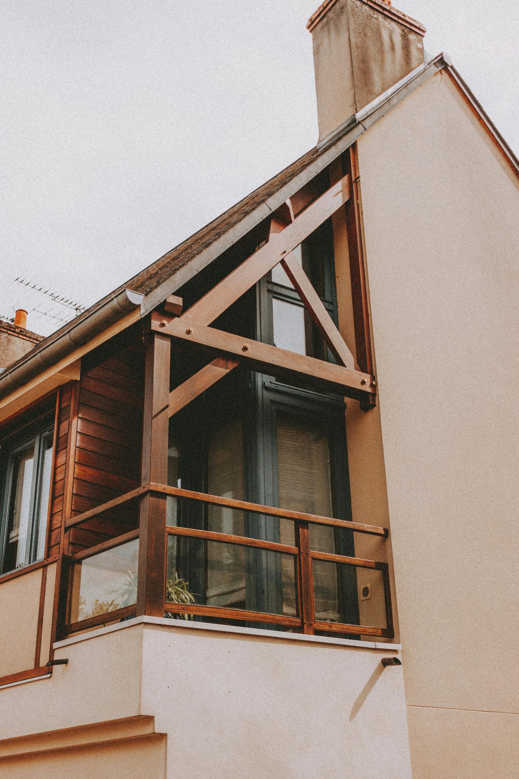 Close-up of a modern house facade featuring wooden accents and a glass balcony.